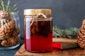 Jar of tasty pine cone jam on dark background, closeup