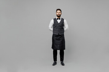 Full body confident young barista male waiter butler man 20s wear white shirt vest elegant uniform...