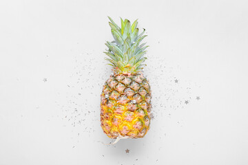 Fresh pineapple with beads and confetti on white background