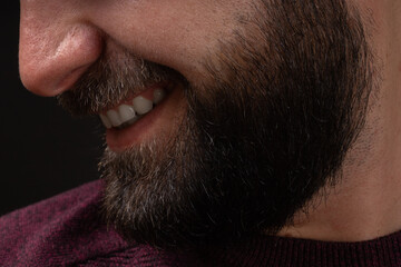 close-up portrait in profile of young smiling, happy man with thick black beard and mustache on...
