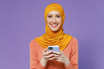 Happy young arabian asian muslim woman in abaya hijab yellow clothes hold in hand use mobile cell...