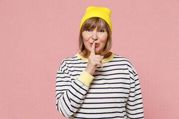 Elderly stylish woman 50s wearing striped shirt yellow hat say hush be quiet with finger on lips...