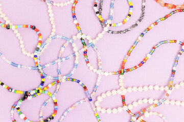 Necklaces and bracelets made from colorful beads and pearls on a purple background.