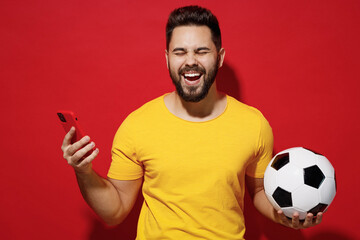 Cheerful young bearded man football fan in yellow t-shirt cheer up support favorite team hold...