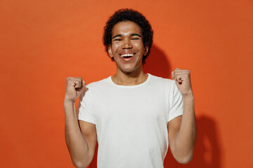 Jubilant excited exultant fun young black curly man 20s years old wears white t-shirt doing winner...