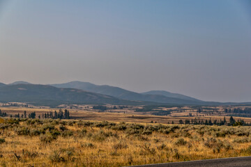 Landscape in Yellowstone National Park on a sunny day smoke from wildfires visible in the background