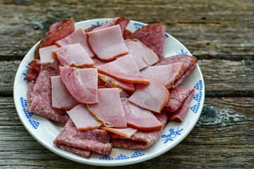 Italian  dried thinly sliced   artisan  pork salami Milano , parmesan cheese, tomatoes   and fresh basil on wooden background .Rustic  home made italian snack.