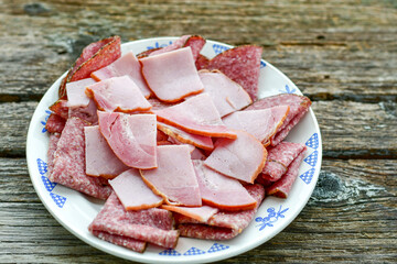 Italian  dried thinly sliced   artisan  pork salami Milano , parmesan cheese, tomatoes   and fresh basil on wooden background .Rustic  home made italian snack.