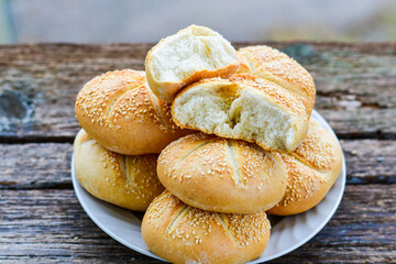 Tasty fresh  crisp  bakery product.   Baked bund bread with sesame seeds on wooden rustic background. Outdoor in a village