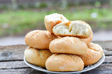 Tasty fresh  crisp  bakery product.   Baked bund bread with sesame seeds on wooden rustic background. Outdoor in a village