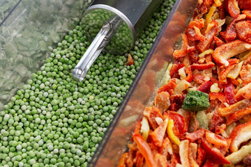 Frozen green peas and red bell peppers in a supermarket. Fresh vegetables and vitamins in winter. Vegetarianism and healthy eating. Close-up.