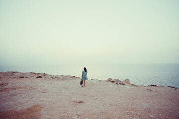 Girl standing on a cliff on the mediterranean sea