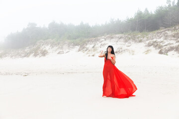 nude woman in red fabric posing on sea beach