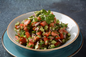 Shirazi Salad with tomatoes, cucumbers, red onions, parsley and mint with fresh lemon juice in a white bowl. Persian Shirazi vegetable salad closeup. Popular Israeli food