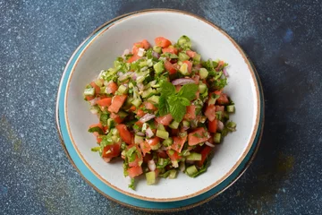  Shirazi Salad with tomatoes, cucumbers, red onions, parsley and mint with fresh lemon juice in a white bowl. Persian Shirazi vegetable salad closeup. Popular Israeli food © Natalia Hanin