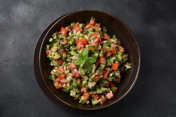Shirazi Salad with tomatoes, cucumbers, red onions, parsley and mint with fresh lemon juice in a...