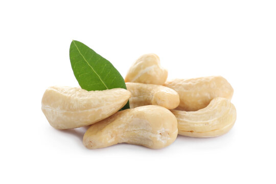 Pile of tasty organic cashew nuts and green leaf isolated on white