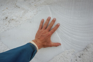 The hand touches the white marble stone