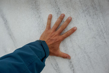 The hand touches the white marble stone