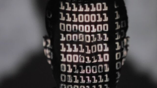 Binary language projected onto the face of an anonymous hacker