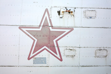 Close-up of the side of an old airplane with a red star on it
