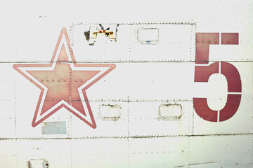 Close-up of the side of an old airplane with a red star and the number five on it
