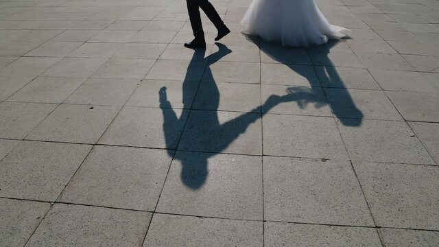 Shadows of a guy and a girl on the ground who are walking around the city. Slow motion shots
