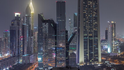 Fototapeta na wymiar Close up view of Dubai Financial Center district with tall skyscrapers illuminated at night timelapse.