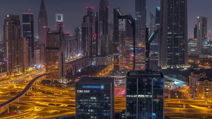 Panorama of Dubai Financial Center district with tall skyscrapers with illumination night to day timelapse.