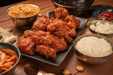 Traditional Korean food, Korean Fried chicken with spicy sauce  with rice, seaweed and Kimchi pickle on wooden table.
