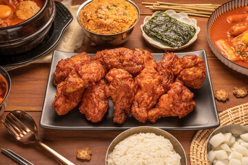 Traditional Korean food, Korean Fried chicken with spicy sauce  with rice, seaweed and Kimchi pickle on wooden table.