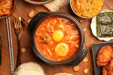 Traditional Korean food, kimchi soup, Korean Fried chicken with spicy sauce  with rice, seaweed,fresh raw crabs marinated,spicy Rice Cake and Kimchi pickle on wooden table.