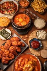 Traditional Korean food, kimchi soup, Korean Fried chicken with spicy sauce  with rice, seaweed,fresh raw crabs marinated,spicy Rice Cake and Kimchi pickle on wooden table.