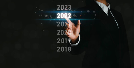 Businesswoman taps the number 2022 to prepare to celebrate the new year to boost business growth and increase business growth and turn it into a Merry Christmas and a Happy New Year.