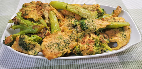 Broccoli cabbage fried in batter served in a white dish on rustic rough tablecloth 