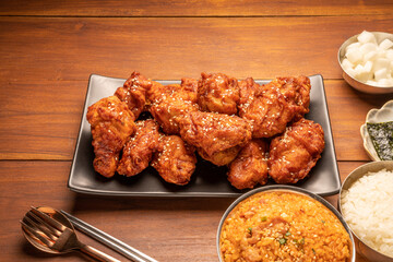 Traditional Korean food, Korean Fried chicken with spicy sauce  with rice, seaweed and Kimchi pickle on wooden table.
