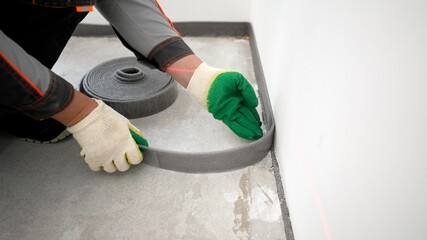 Bonding the floor with a damper tape. Installing a damping tape. Damping tape for floor screed....
