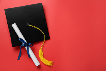 Graduation hat and diploma on red background, flat lay. Space for text