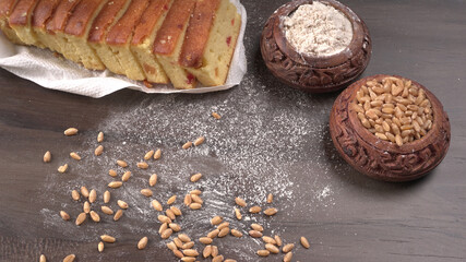 Slices of home made wholemeal bread on a white background with wheat and flour.