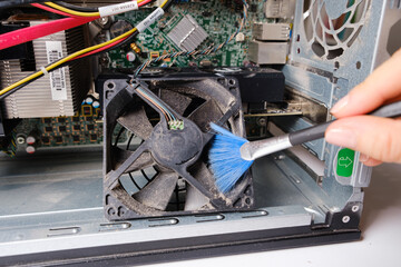 A computer master cleans the dust of the cooler of the ventilation of the system unit