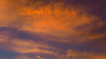 Fototapeta na wymiar Somptueuses traînées de lumière rouges et oranges, sous des nuages de type Cirrus et Cirrostratus