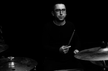 Young beraded man in glasses playing drums	