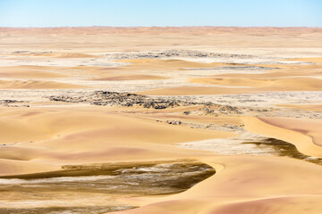 A horizontal rocky desert landscape of golden sand dunes, aerial shot from an aeroplane of the Namibian desert landscape 