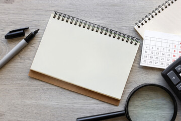 open notebook with calendar magnifier and pens