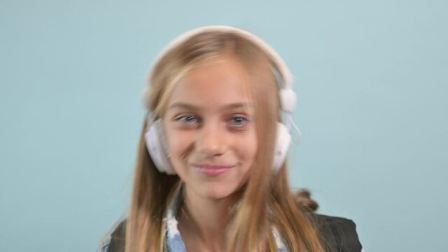 Young blonde girl with blue eyes listening to music with headphones.