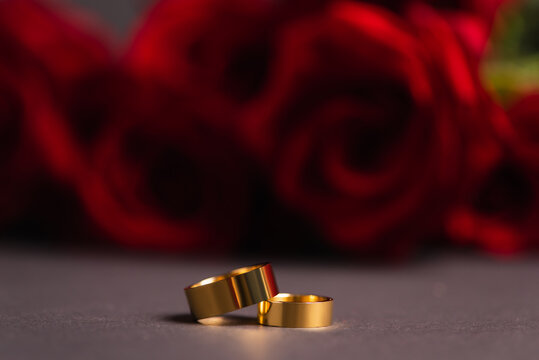 golden wedding rings with blurred roses on background.