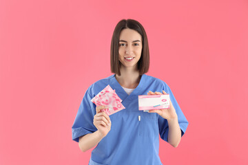 Female nurse with pads and pregnancy test on pink background
