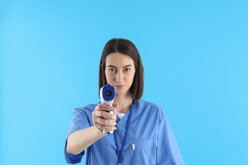 Female nurse with thermometer gun on blue background