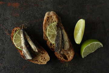 Delicious sandwiches with sprats on textured background