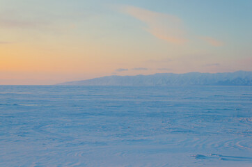 Fototapeta na wymiar View of the freezing Lake Baikal in the snow at sunset.